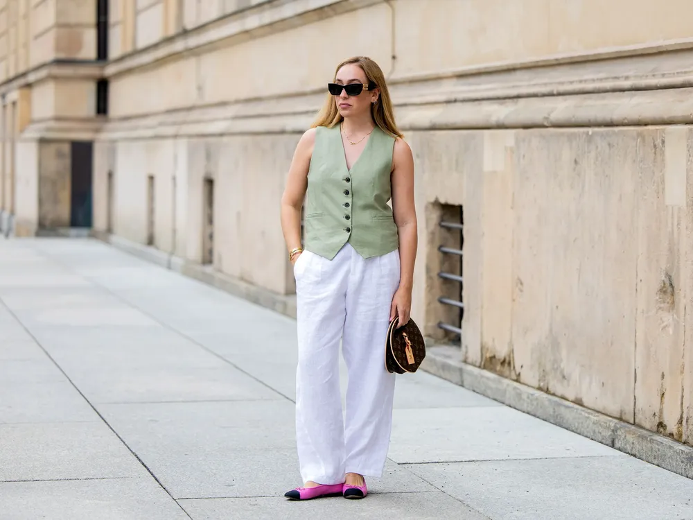 mujer-con-pantalones-de-lino-blannco-chaleco-verde-y-bailarinas-rosa