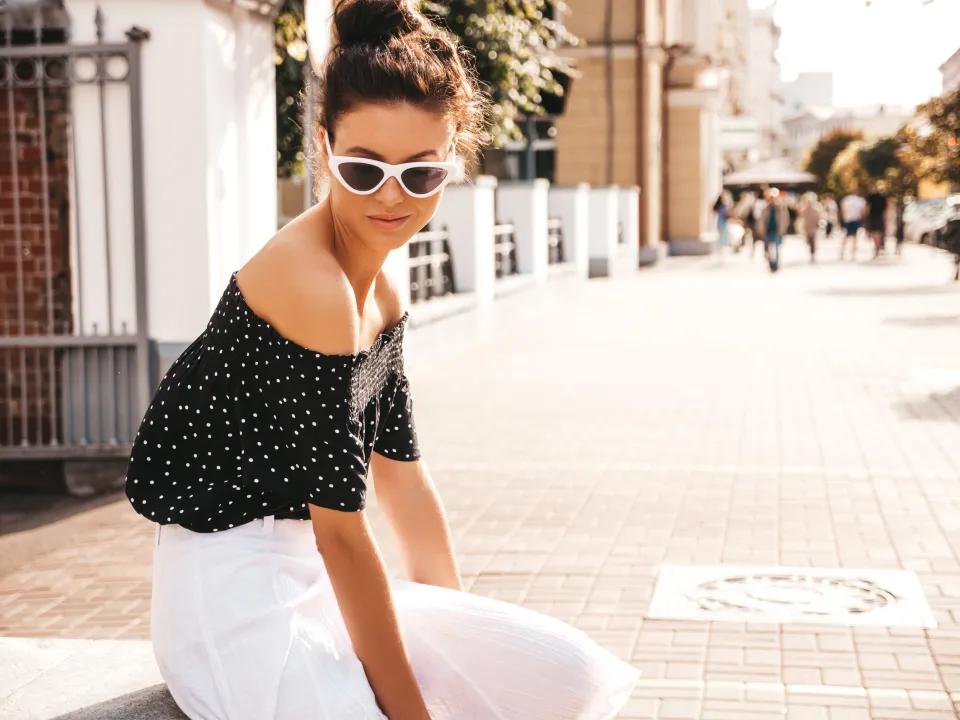 hermosa-modelo-sonriente-vestida-con-ropa-elegante-de-verano-chica-despreocupada-sexy-sentada-en-la-calle-empresaria-moderna-moderna-en-gafas-de-sol-divirtiendose